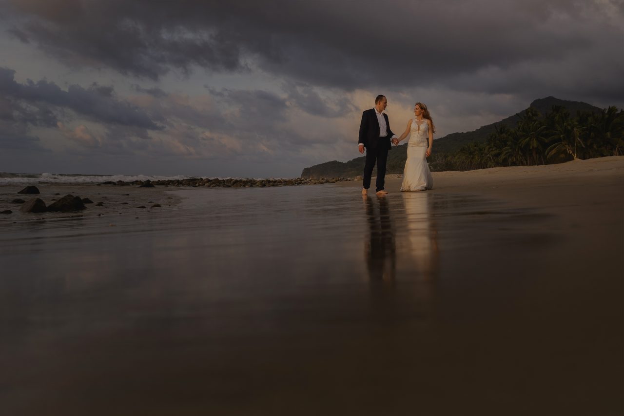 Couple walking barefoot on the beach at sunset during a destination wedding in Mexico