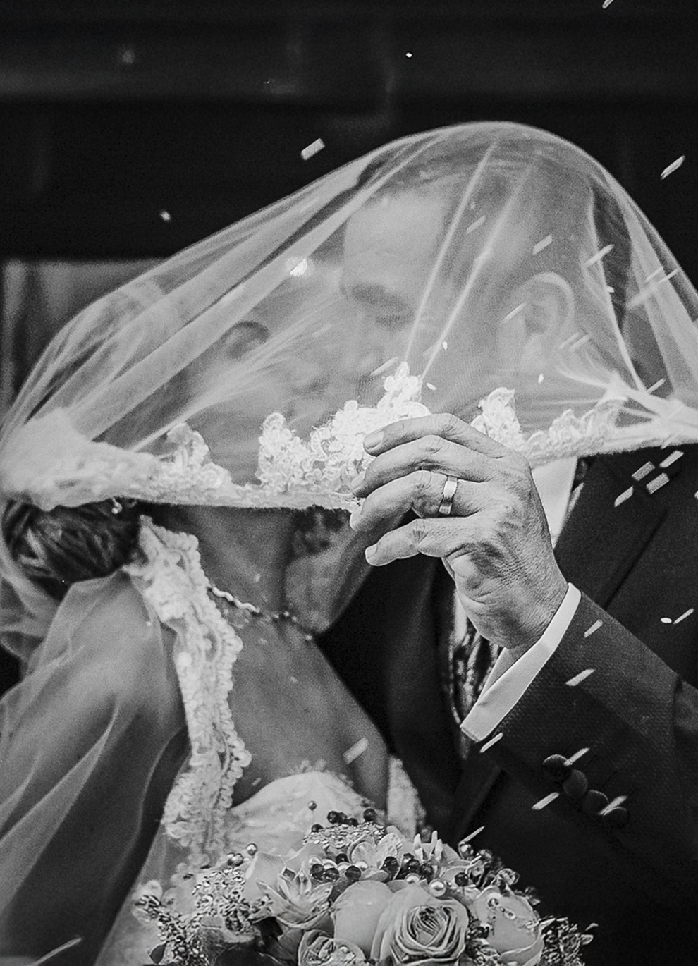 Bride and groom sharing a kiss under the veil during a wedding ceremony in Mexico, captured in black and white documentary style