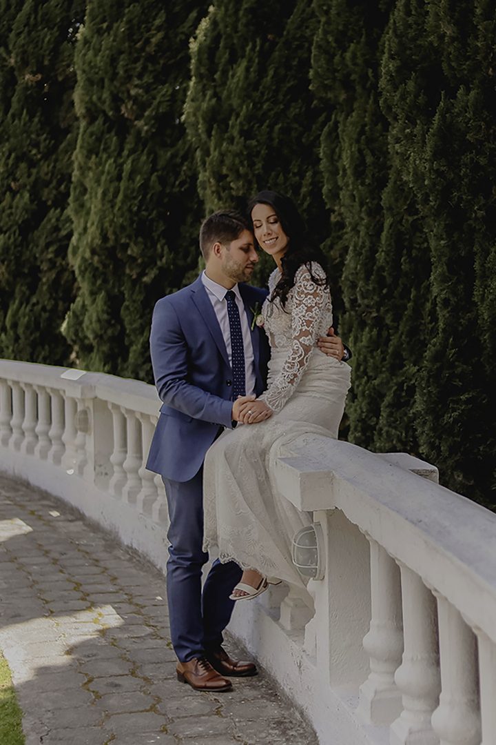 Bride in mermaid wedding dress sitting on white railing with groom in Quito Ecuador destination wedding photography